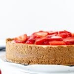 Cheesecake with strawberry topping and a graham crumb crust around the sides.