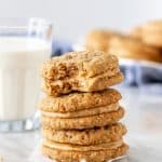 Stack of peanut butter sandwich cookies with glass of milk.