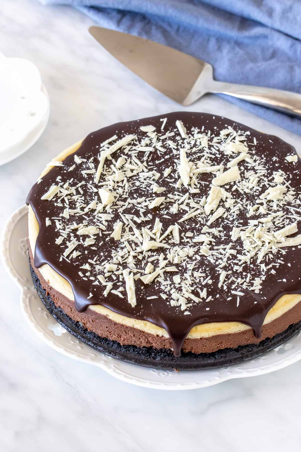 Cheesecake topped with chocolate ganache and white chocolate shavings