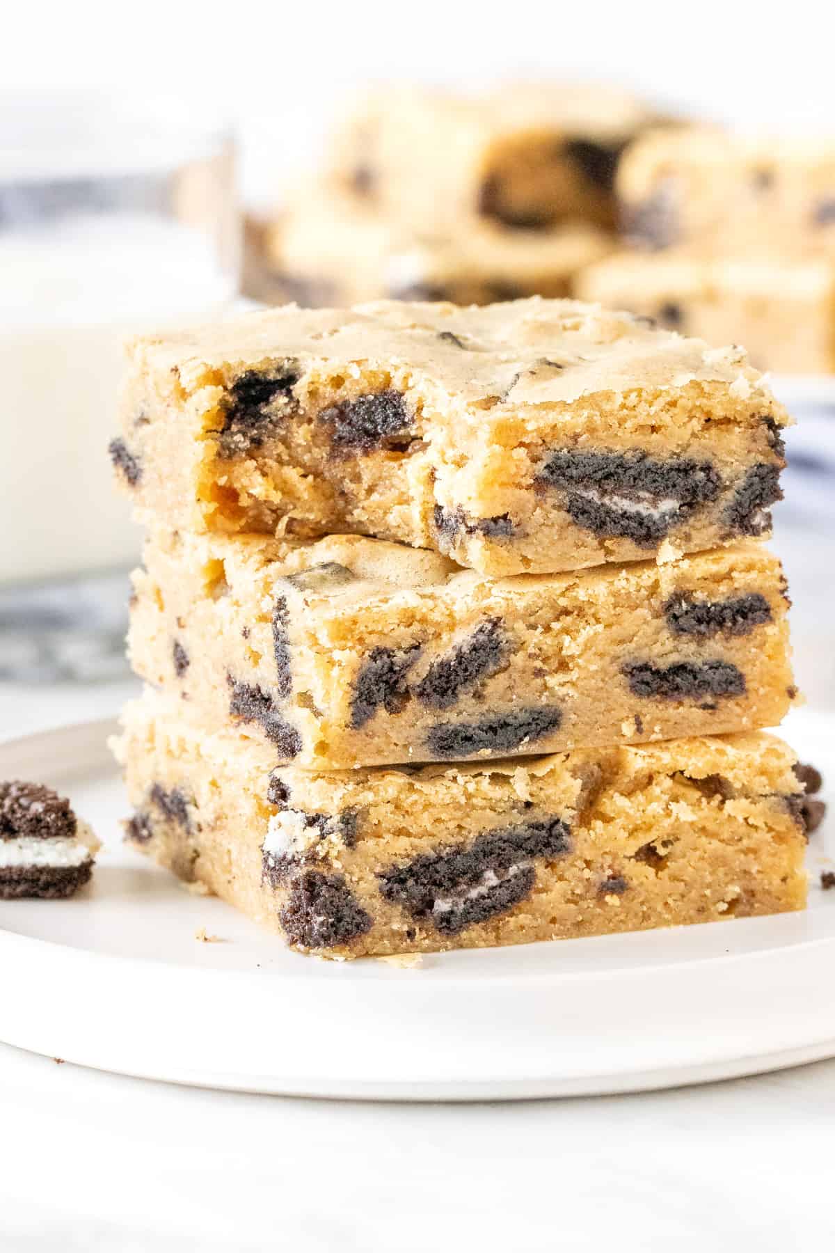Stack of Oreo blondies on a plate with a glass of milk