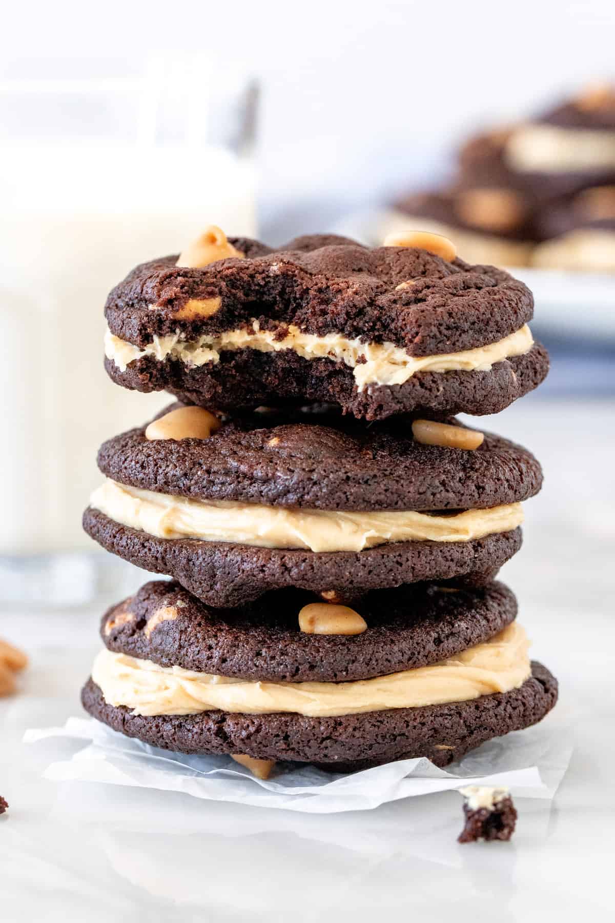 Stack of 3 chocolate peanut butter sandwich cookies with a glass of milk