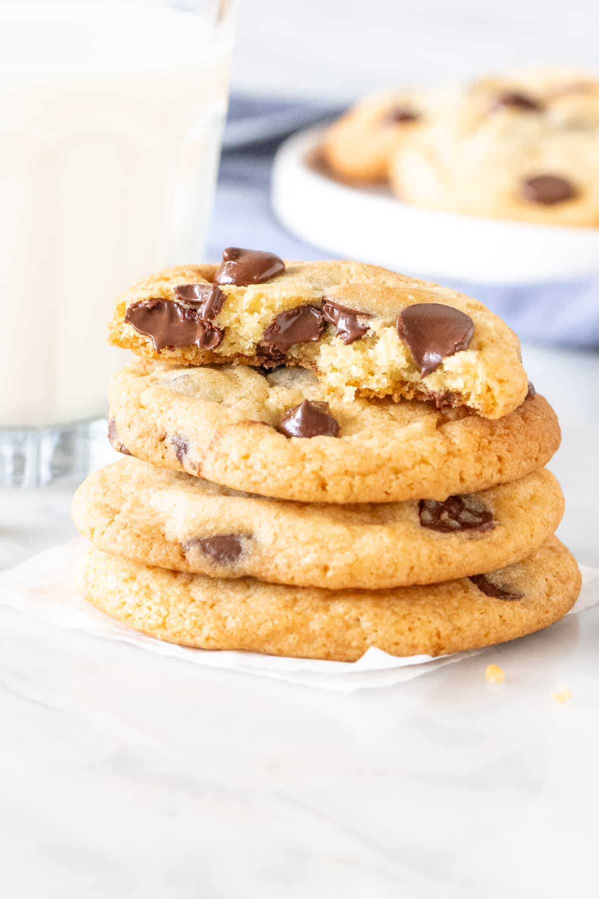 Stack of chewy chocolate chip cookies, with the top cookie broken in half