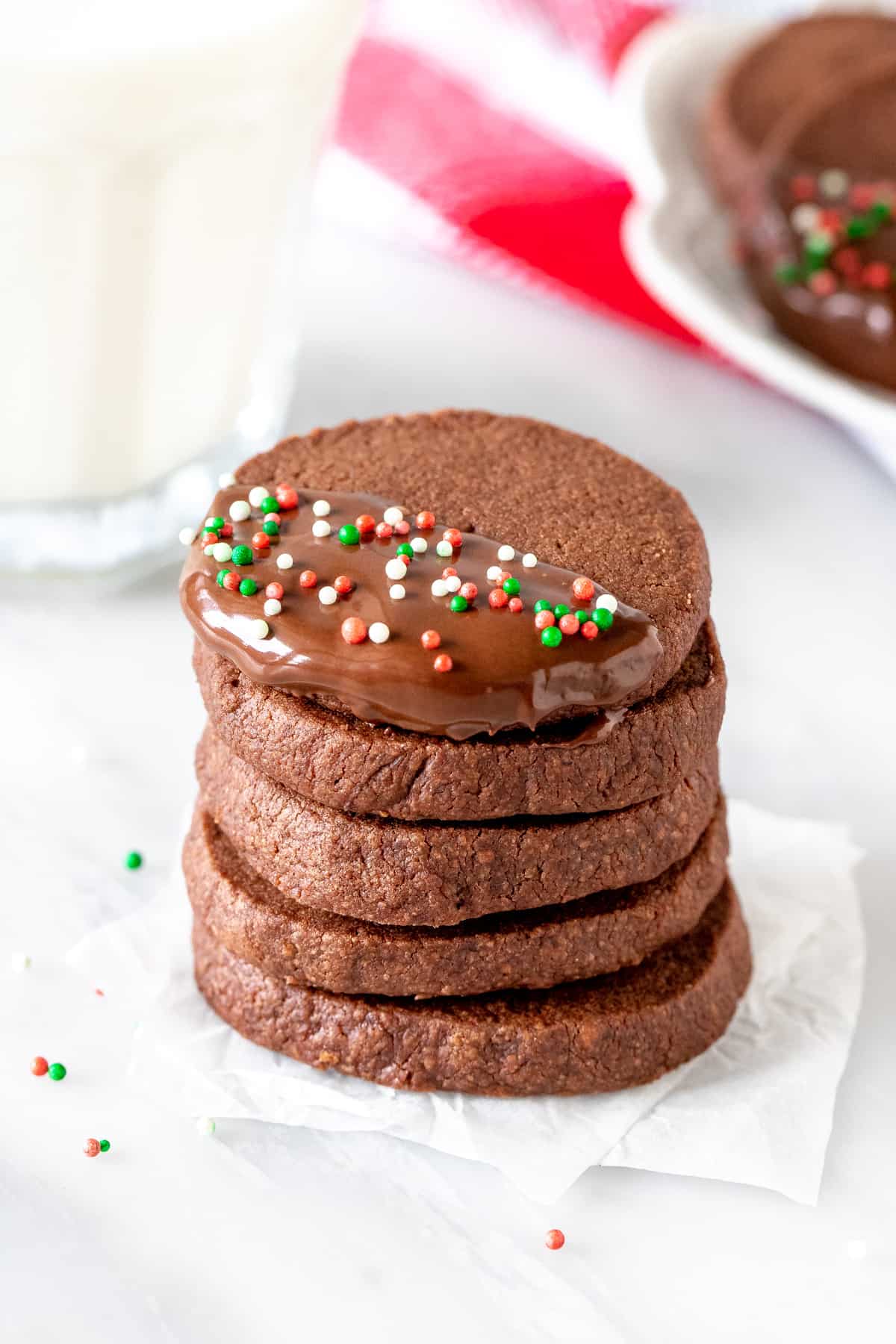 Stack of Christmas chocolate shortbread with glass of milk.