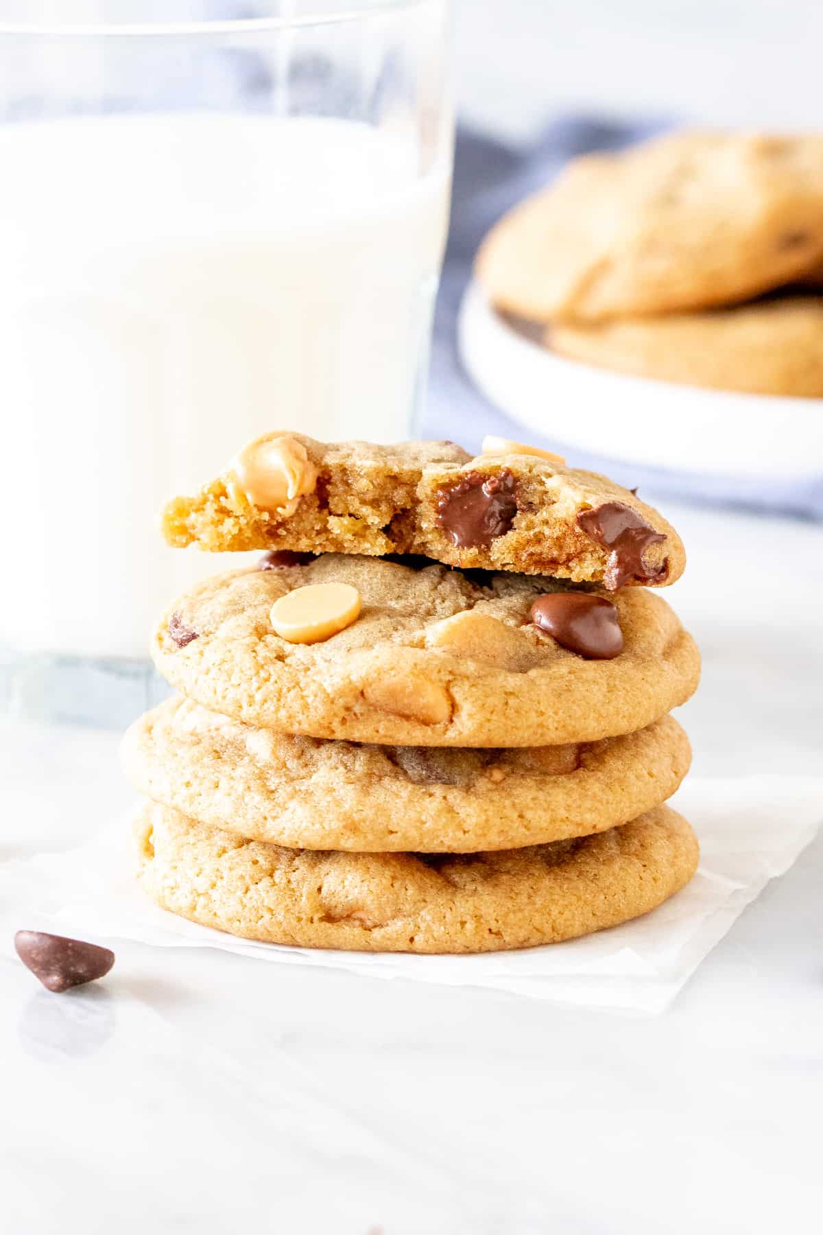 Stack of butterscotch chocolate chip cookies with glass of milk