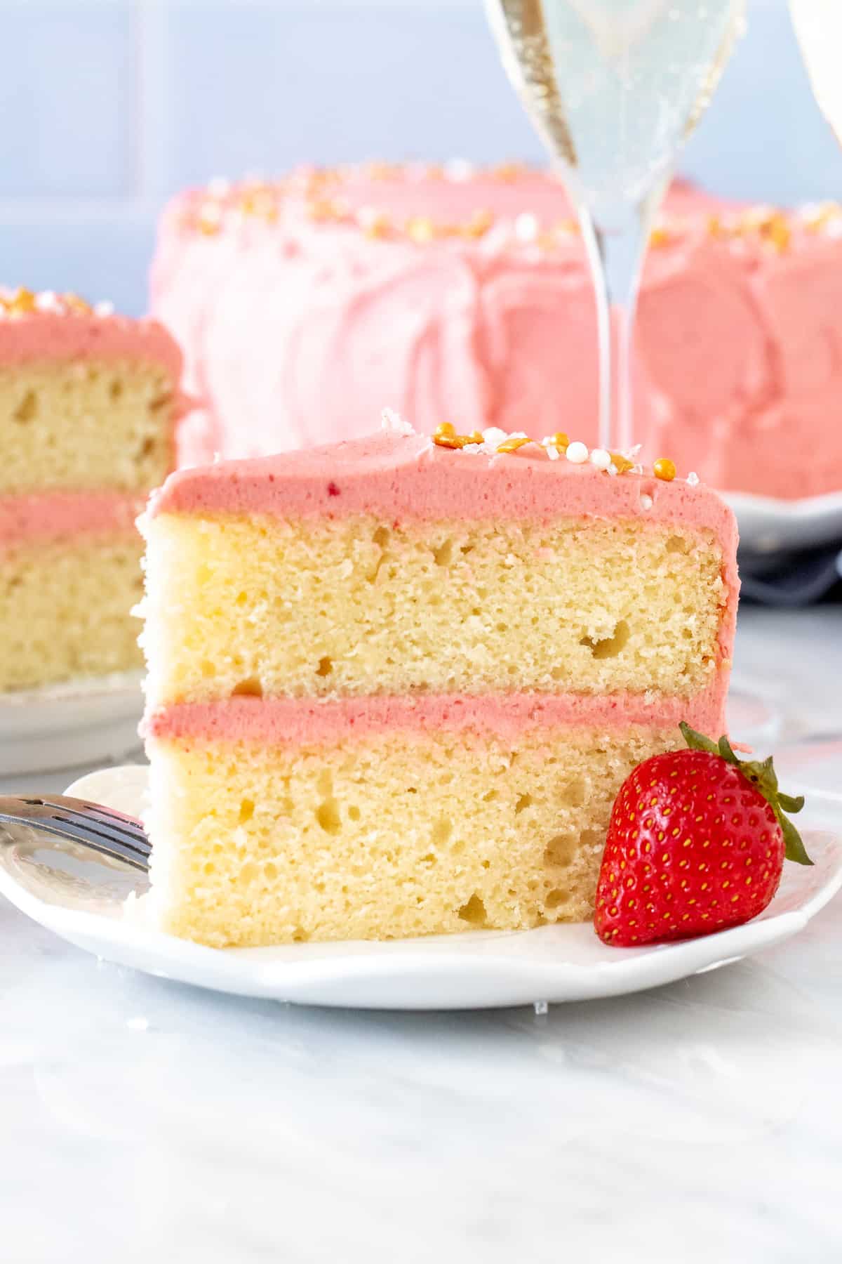 Slice of champagne layer cake with strawberry frosting