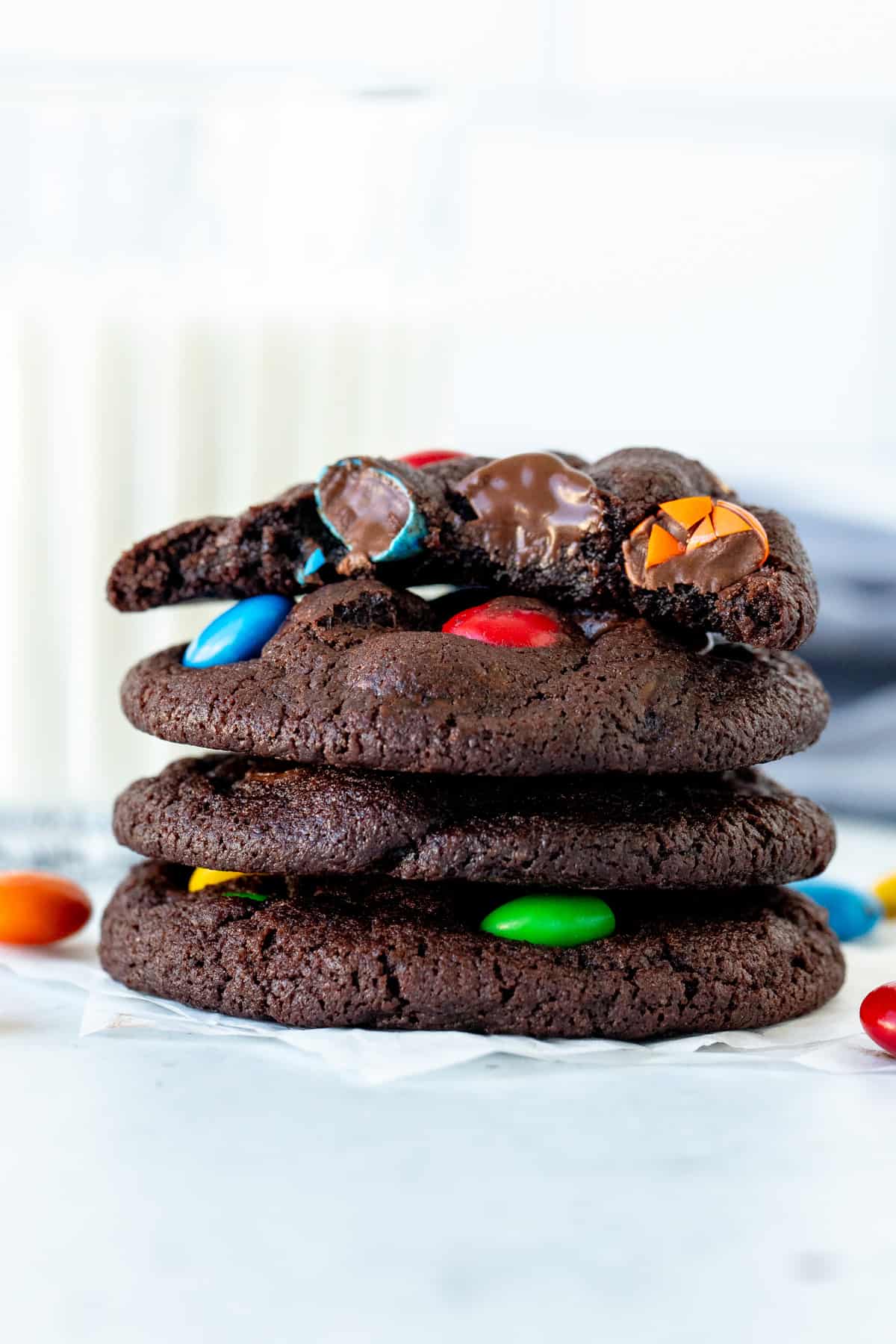 Stack of chocolate M&M cookies with top cookie broken in half
