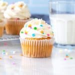Cupcake with bright white frosting and glass of milk
