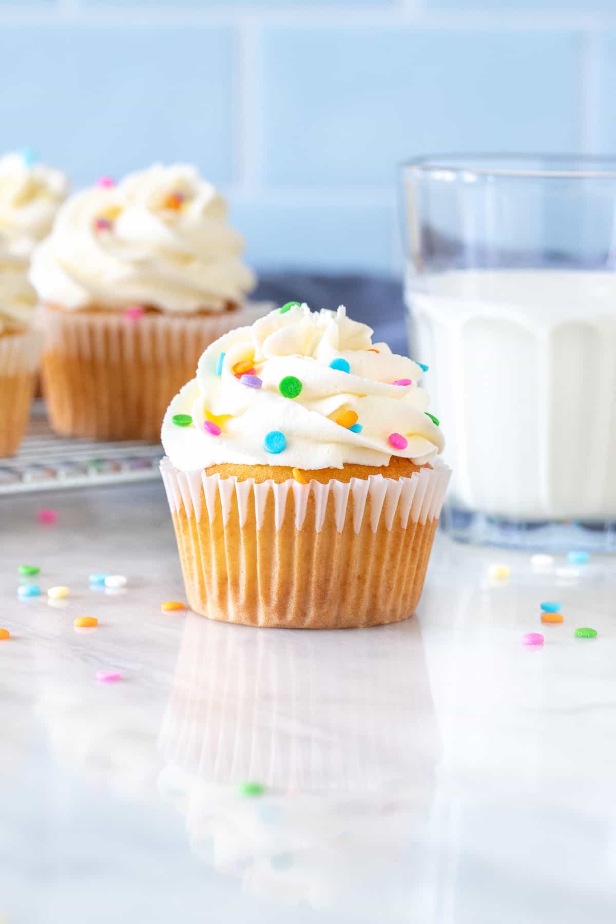 Cupcake with bright white frosting and glass of milk