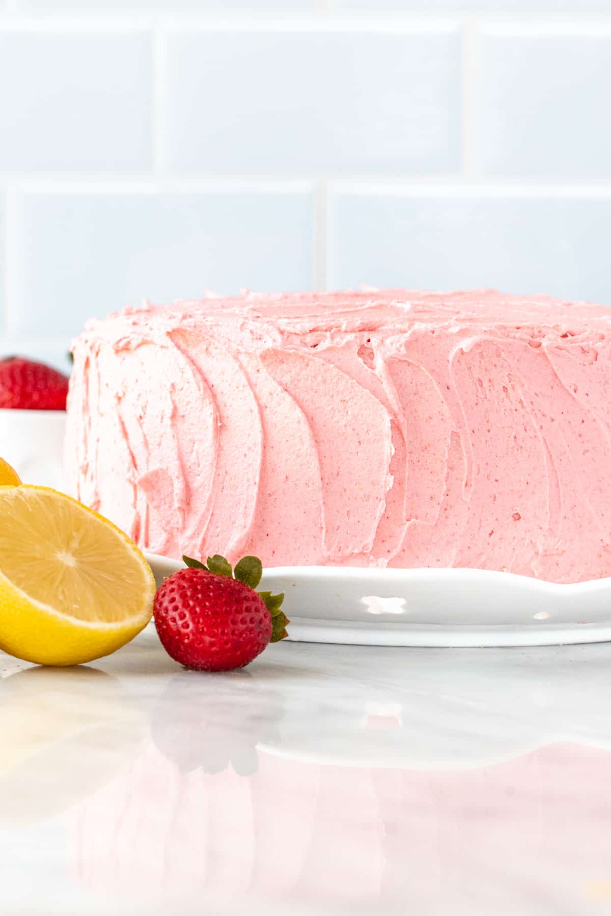 Strawberry lemon cake on a round cake plate.