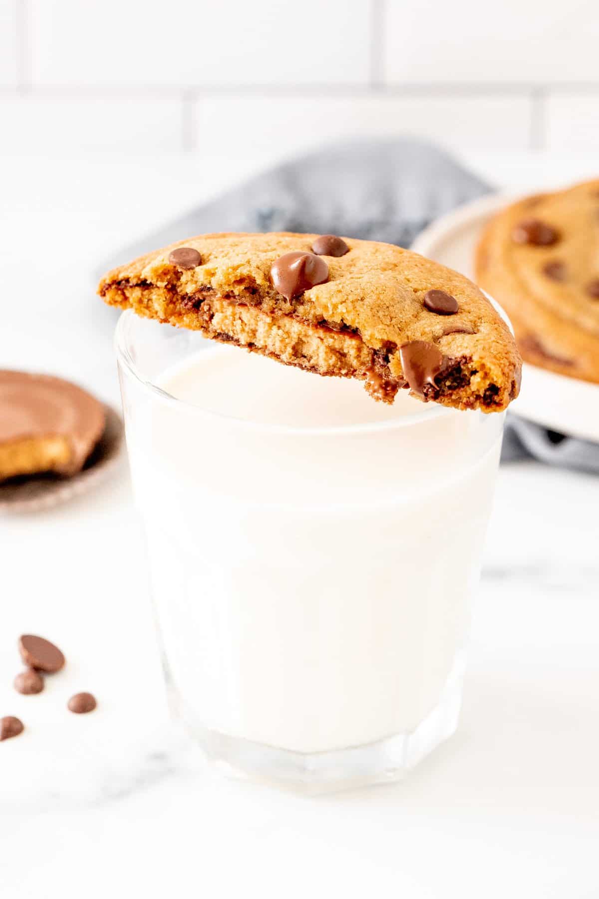 Half of a reese's cookie on top of a glass of milk