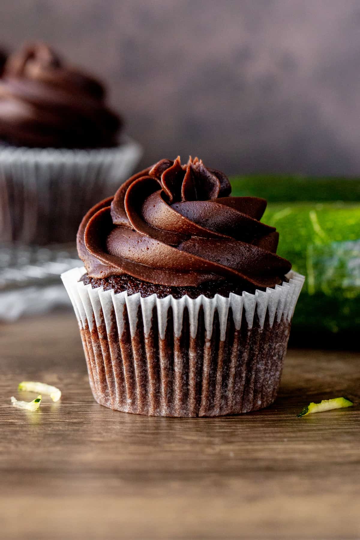 Chocolate zucchini cupcake with zucchini and cupcakes in background