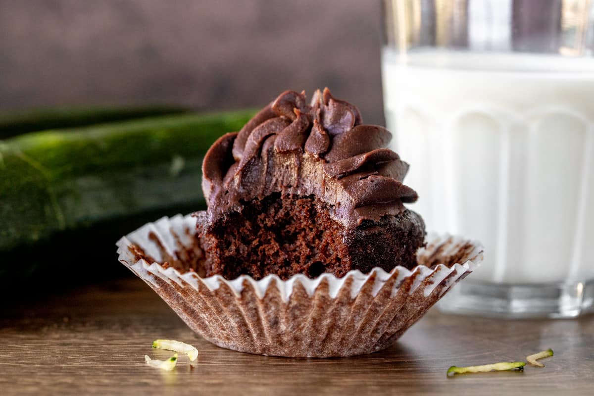 Chocolate cupcake with a bite taken out with glass of milk
