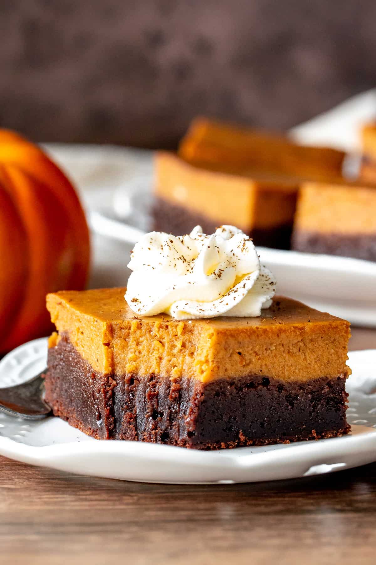 Layered pumpkin pie brownie with whipped cream on top on a plate