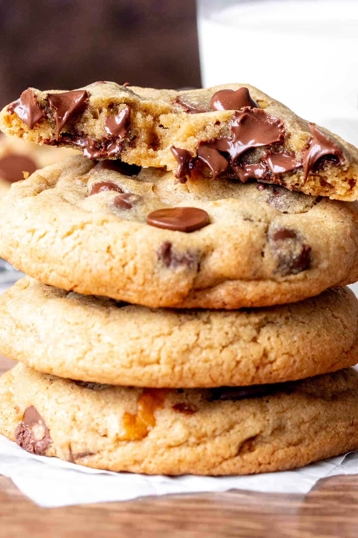 4 walnut chocolate chip cookies on top of each other, with top cookie broken in half