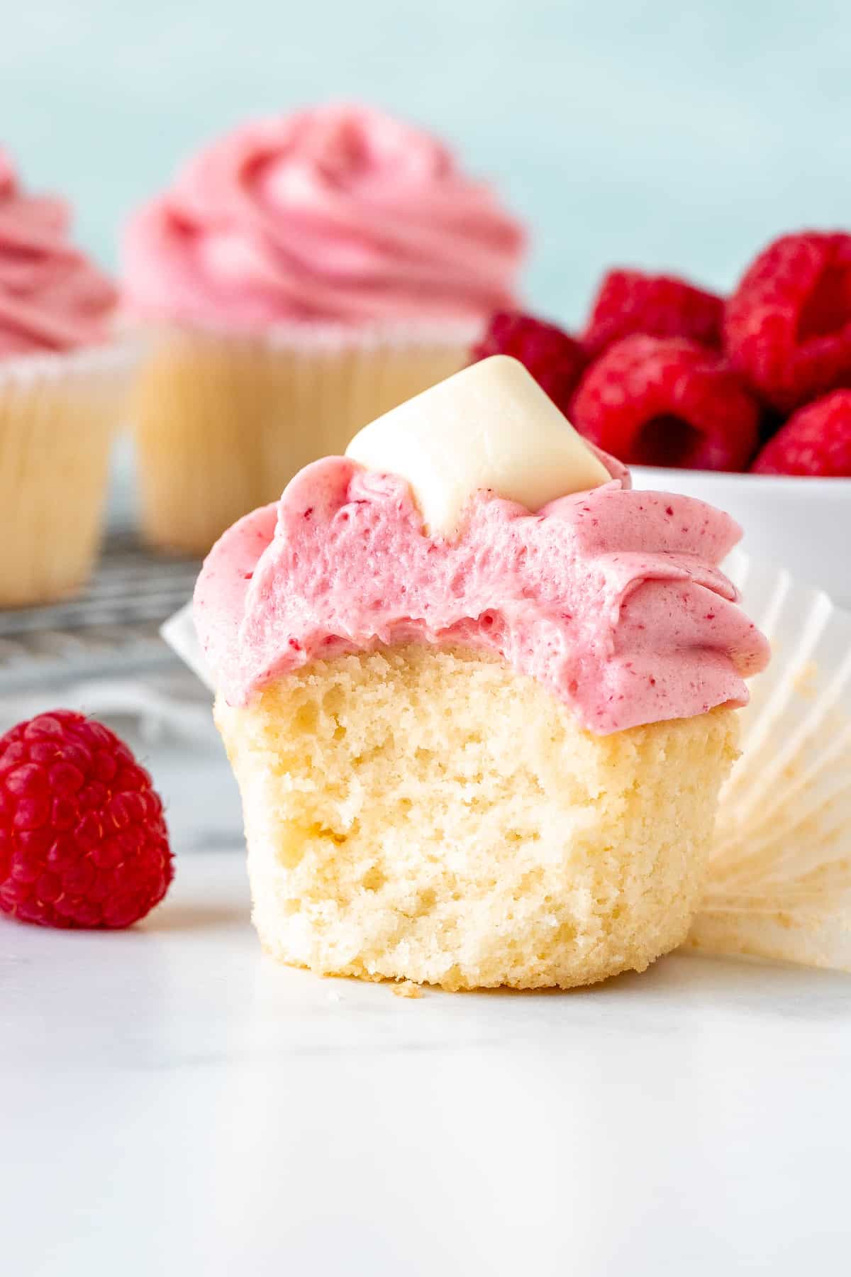 White chocolate cupcake with raspberry frosting with a bite taken out