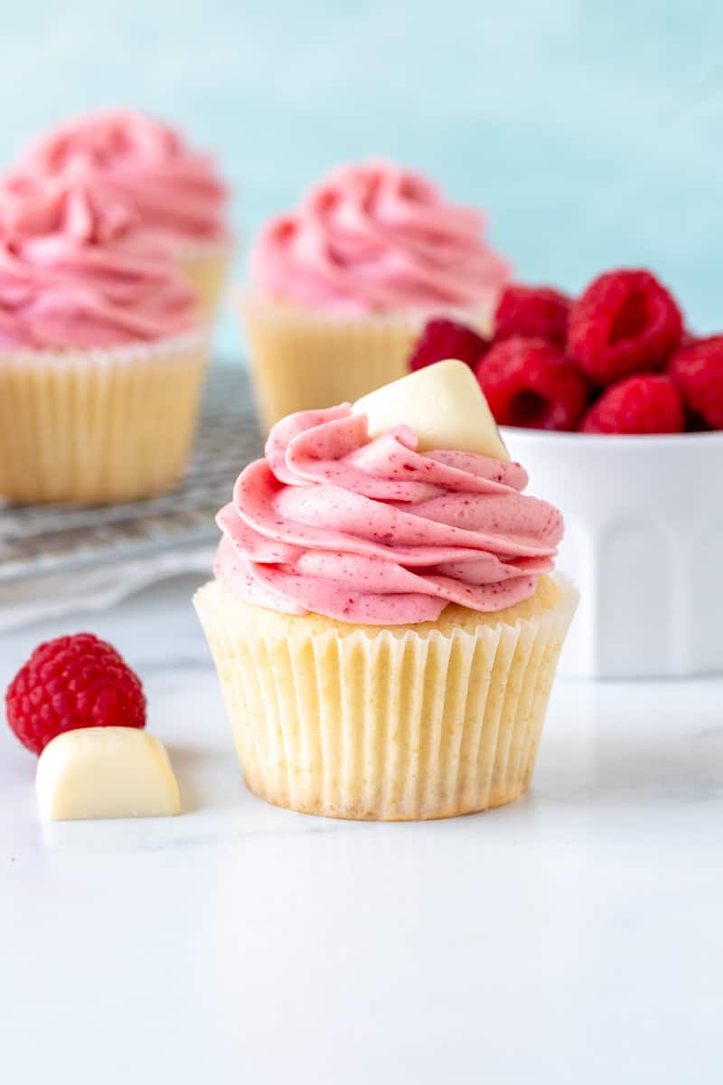 White chocolate cupcake with raspberry frosting with square of white chocolate on top