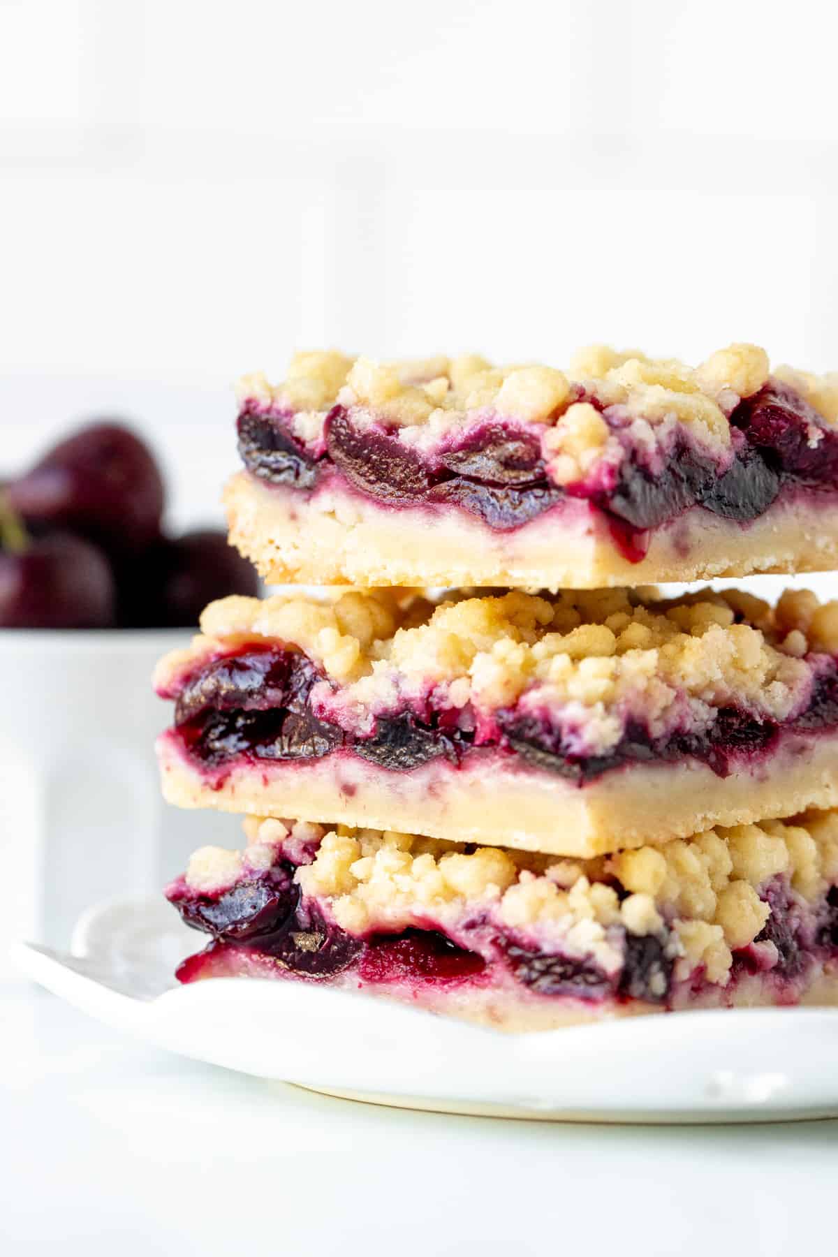 Three cherry shortbread bars with crumb topping, stacked one on top of eachother