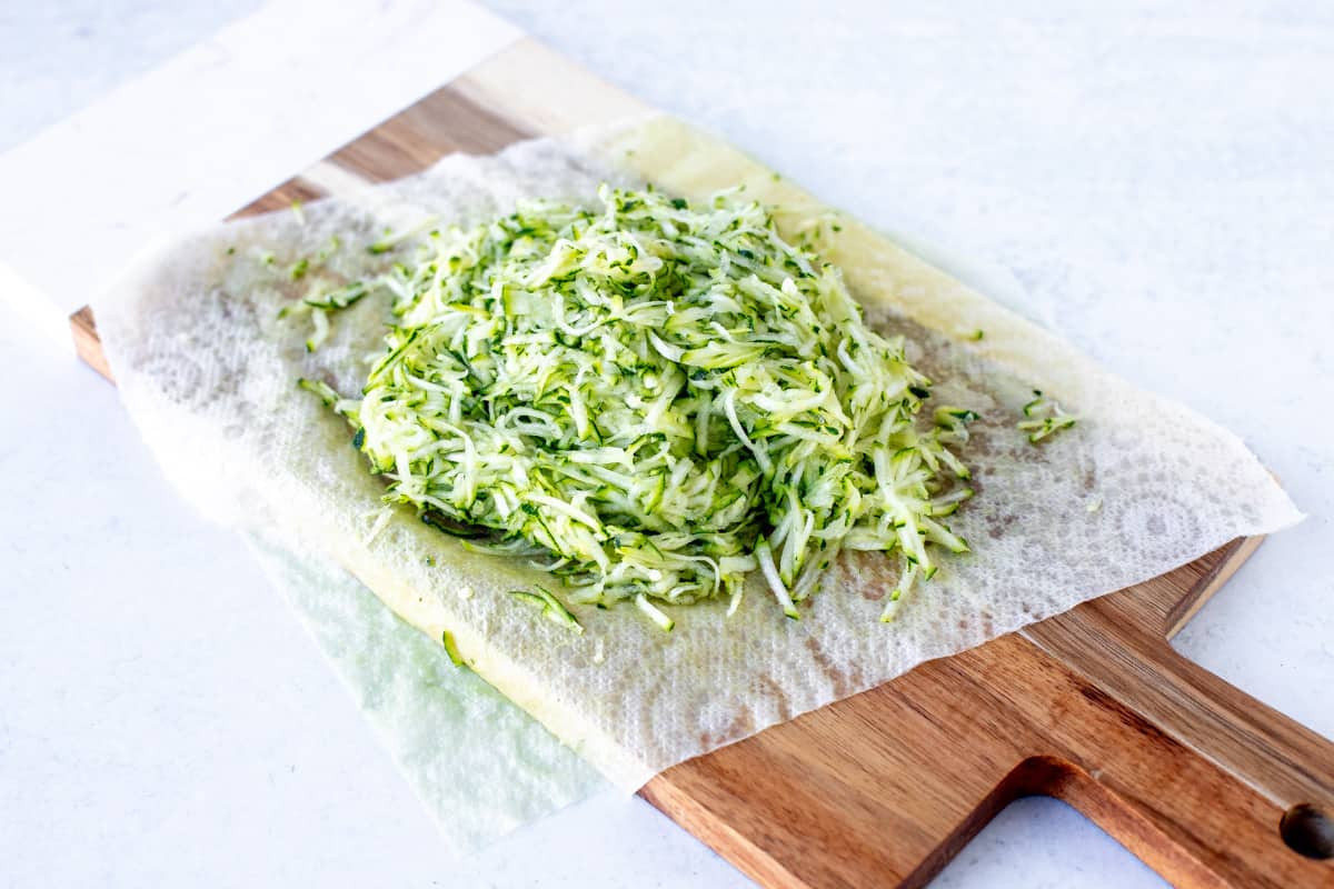 Finely grated zucchini on wooden chopping board
