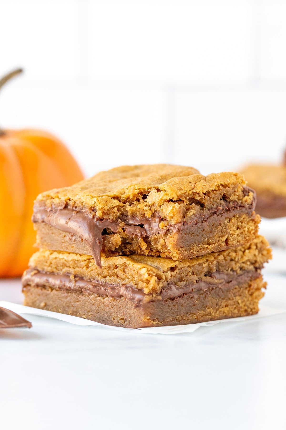 Stack of two Nutella pumpkin blondies, with a bite taken out of the blondie on top