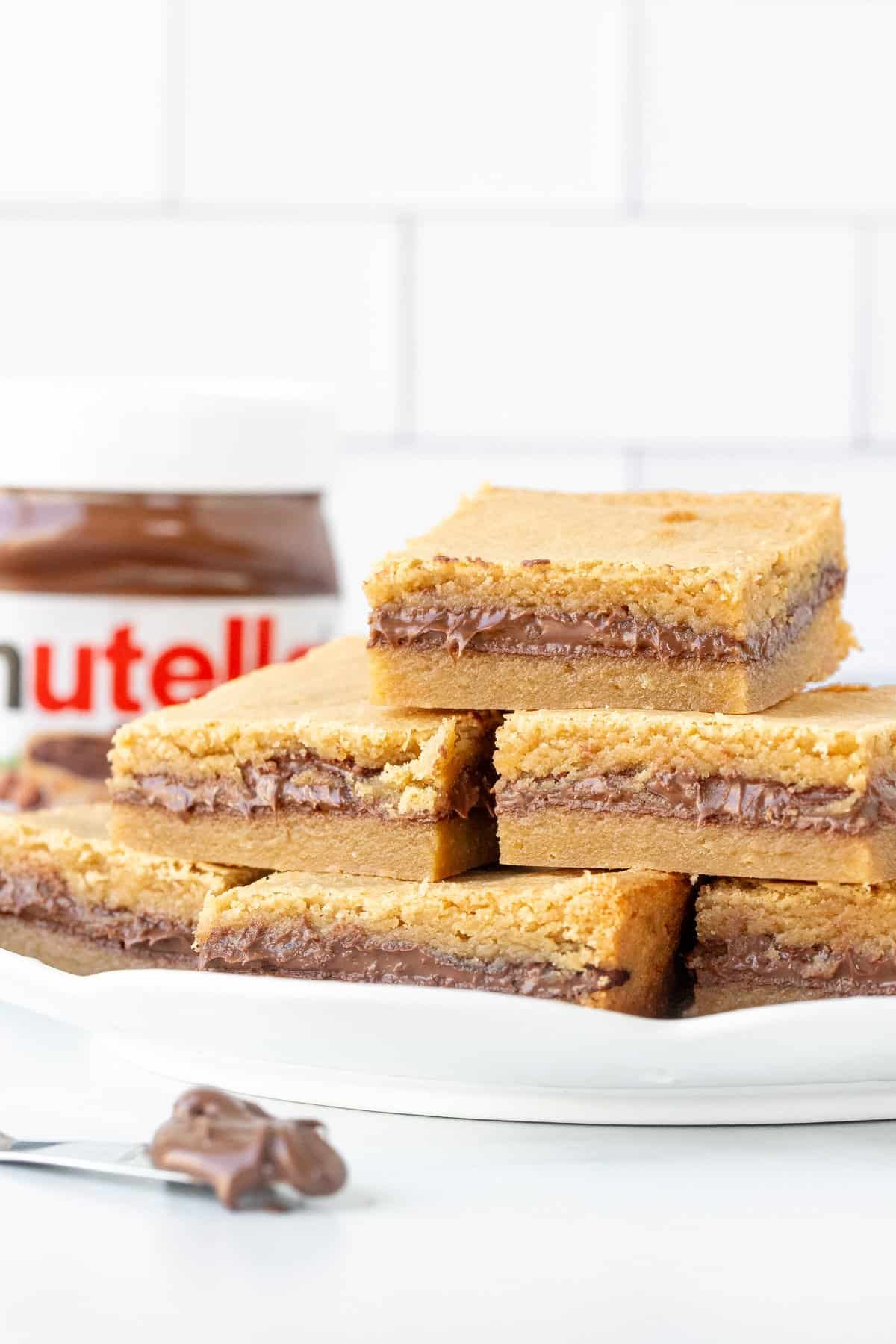 Plate of Nutella blondies with jar of Nutella