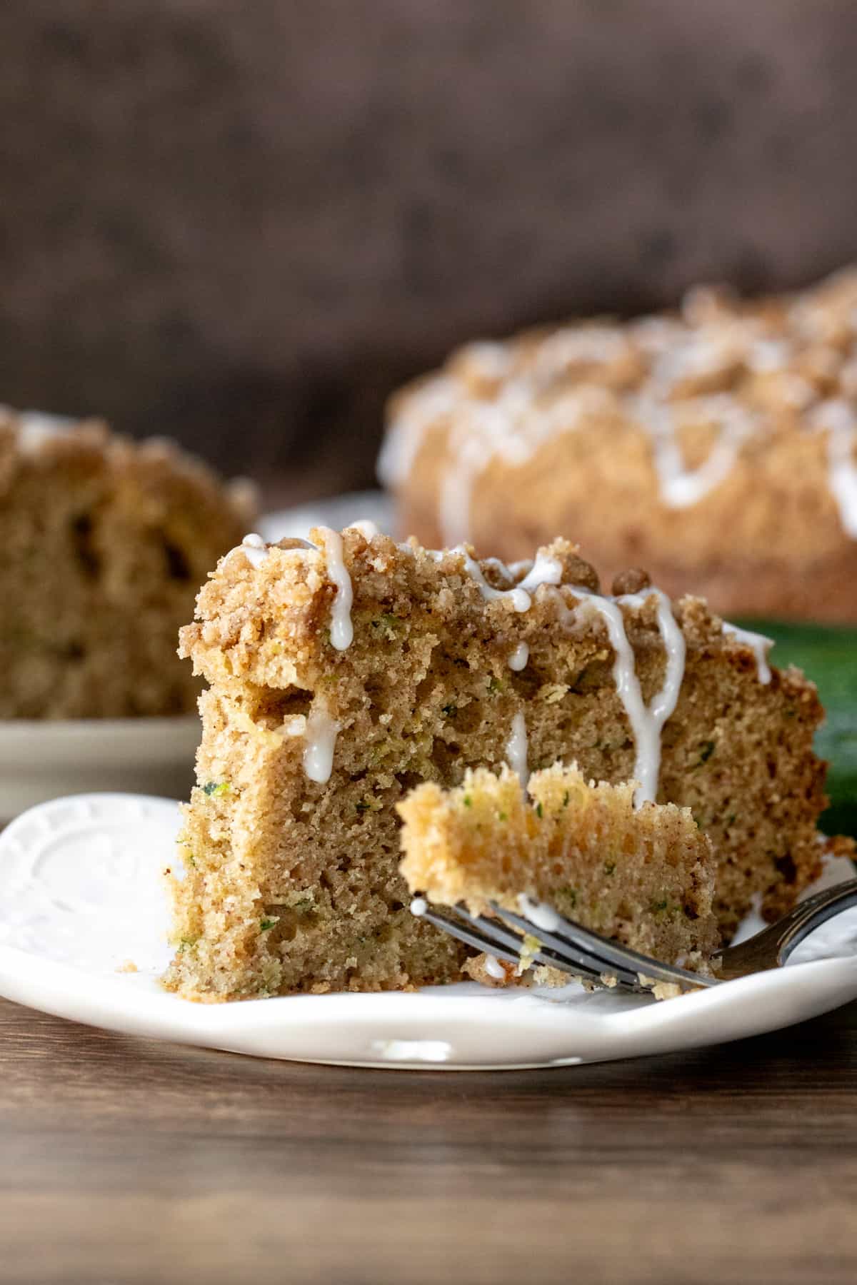 Piece of zucchini coffee cake with streusel topping and a drizzle of glaze