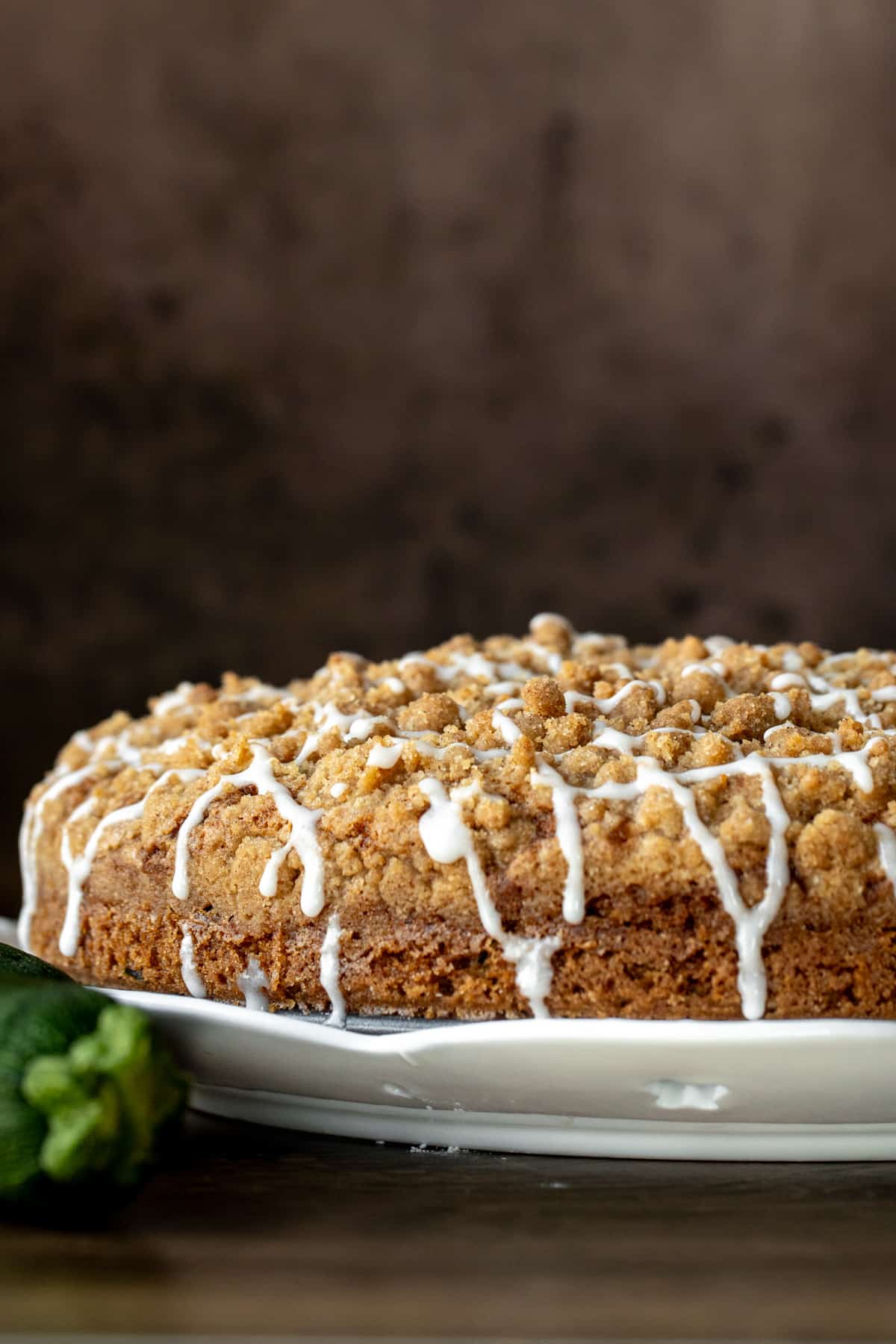 9-inch round zucchini coffee cake with a drizzle of glaze on a white plate