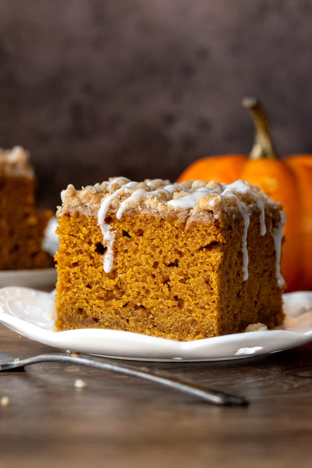 Slice of pumpkin coffee cake with streusel topping with a drizzle of glaze