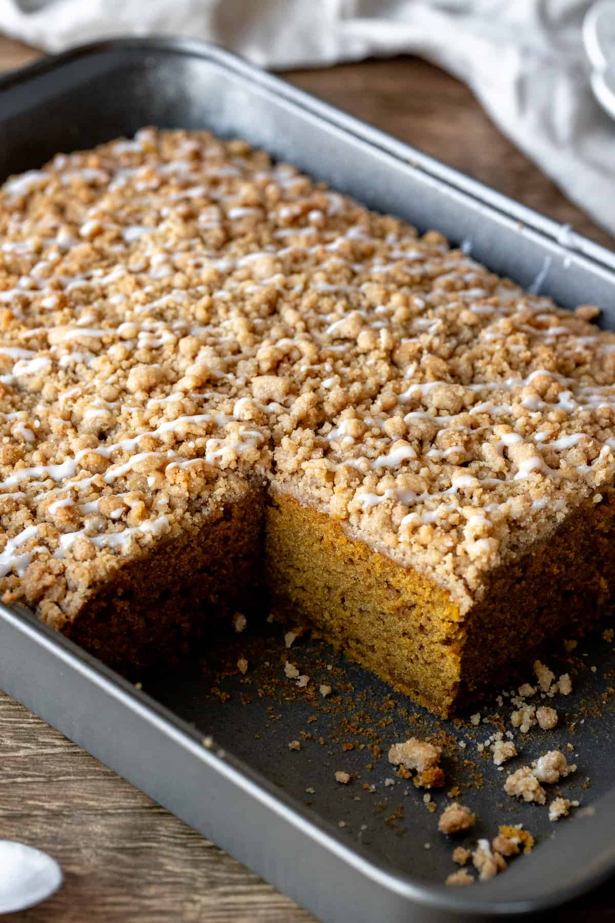 Pan of pumpkin coffee cake with streusel topping and drizzle of glaze