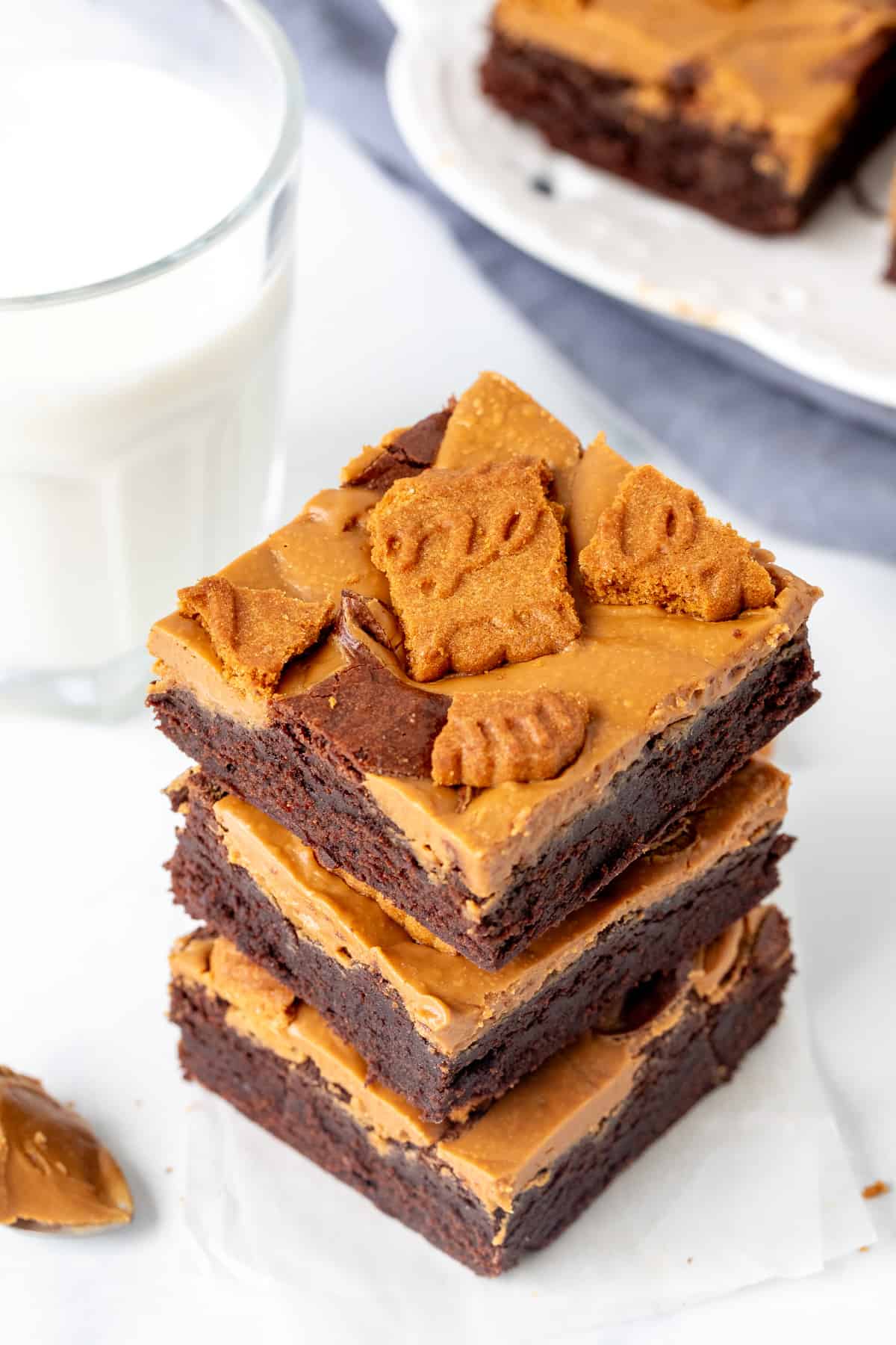 Three cookie butter brownies stacked on top of each other with a glass of milk