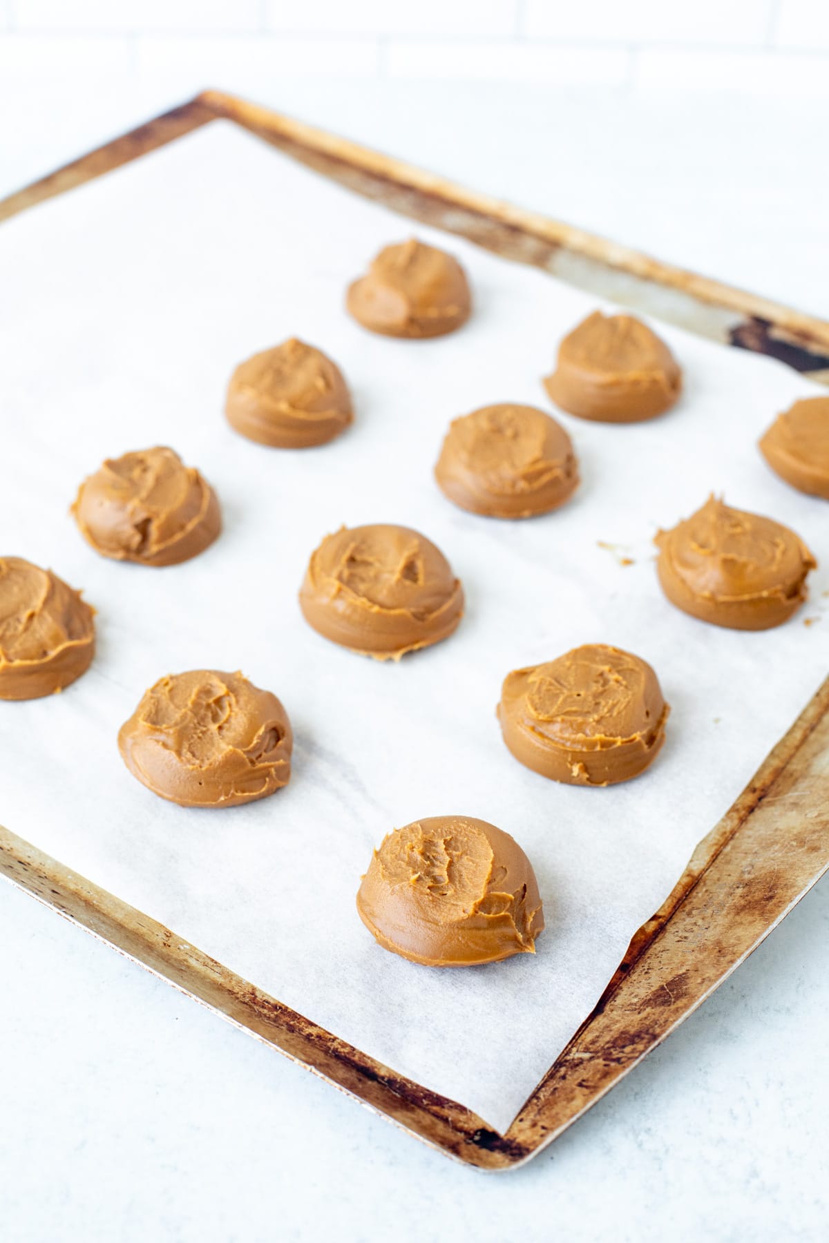 Spoonfulls of cookie butter on a lined cookie sheet