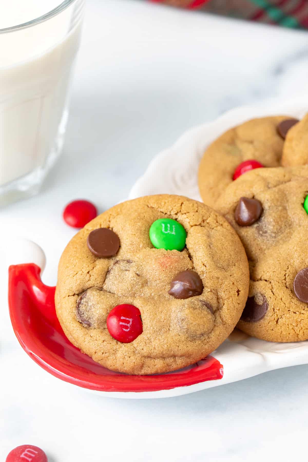 Christmas M&M peanut butter cookies on a Santa plate with a glass of milk