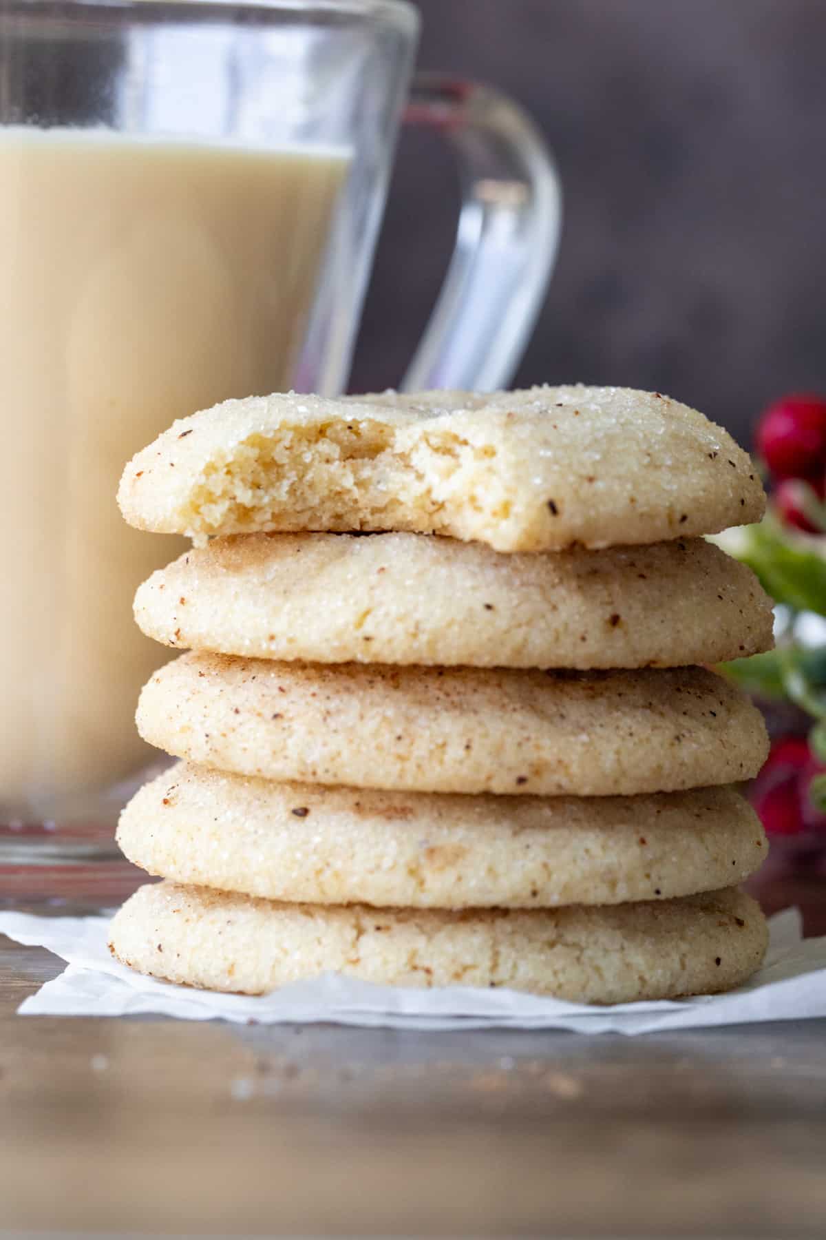 Stack of eggnog cookies with a bite taken out of the cookie on top