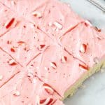 Pan of frosted peppermint sugar cookie bars with crushed candy canes on top