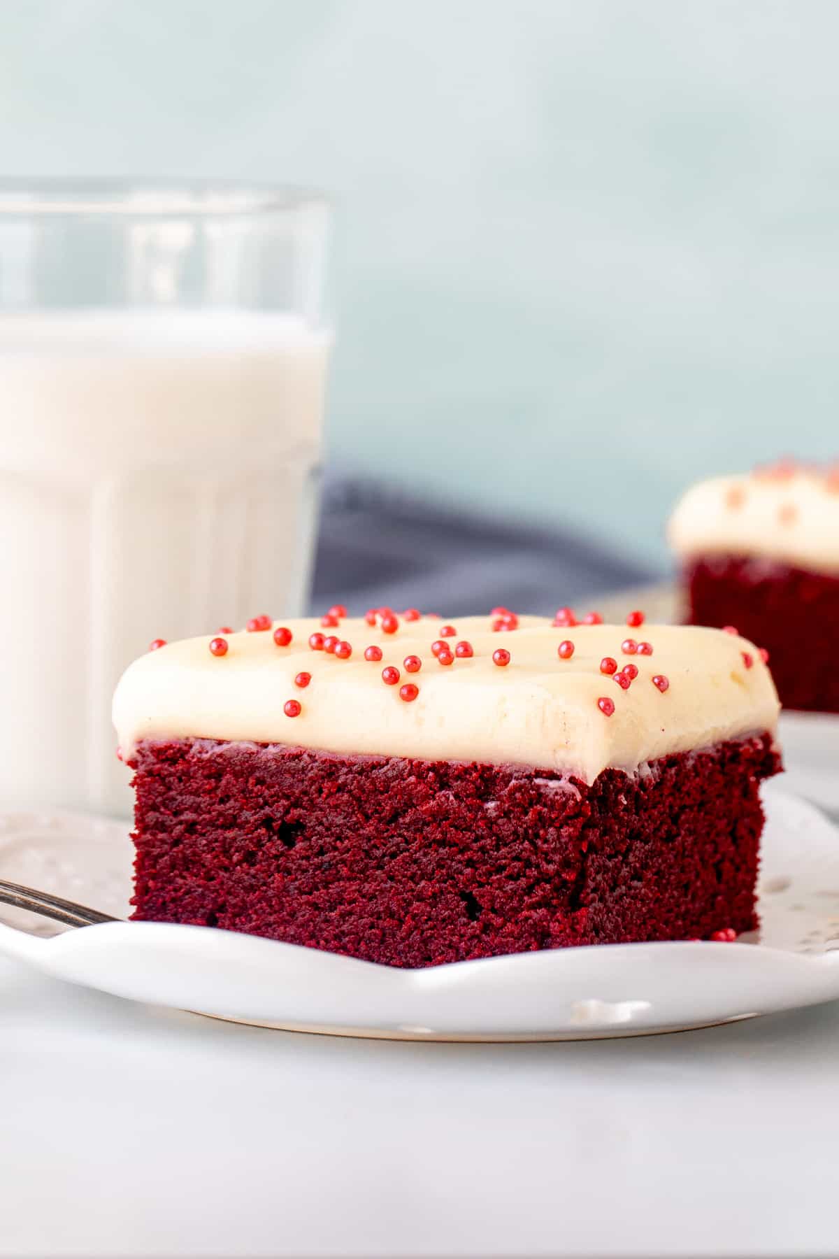 Red velvet brownie topped with cream cheese frosting with glass of milk