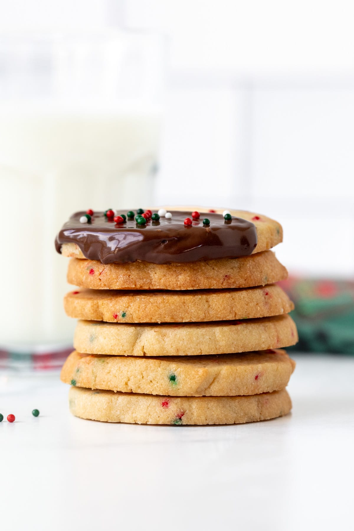 Stack of Christmas sprinkle slice and bake cookies, with top cookie dipped in chocolate