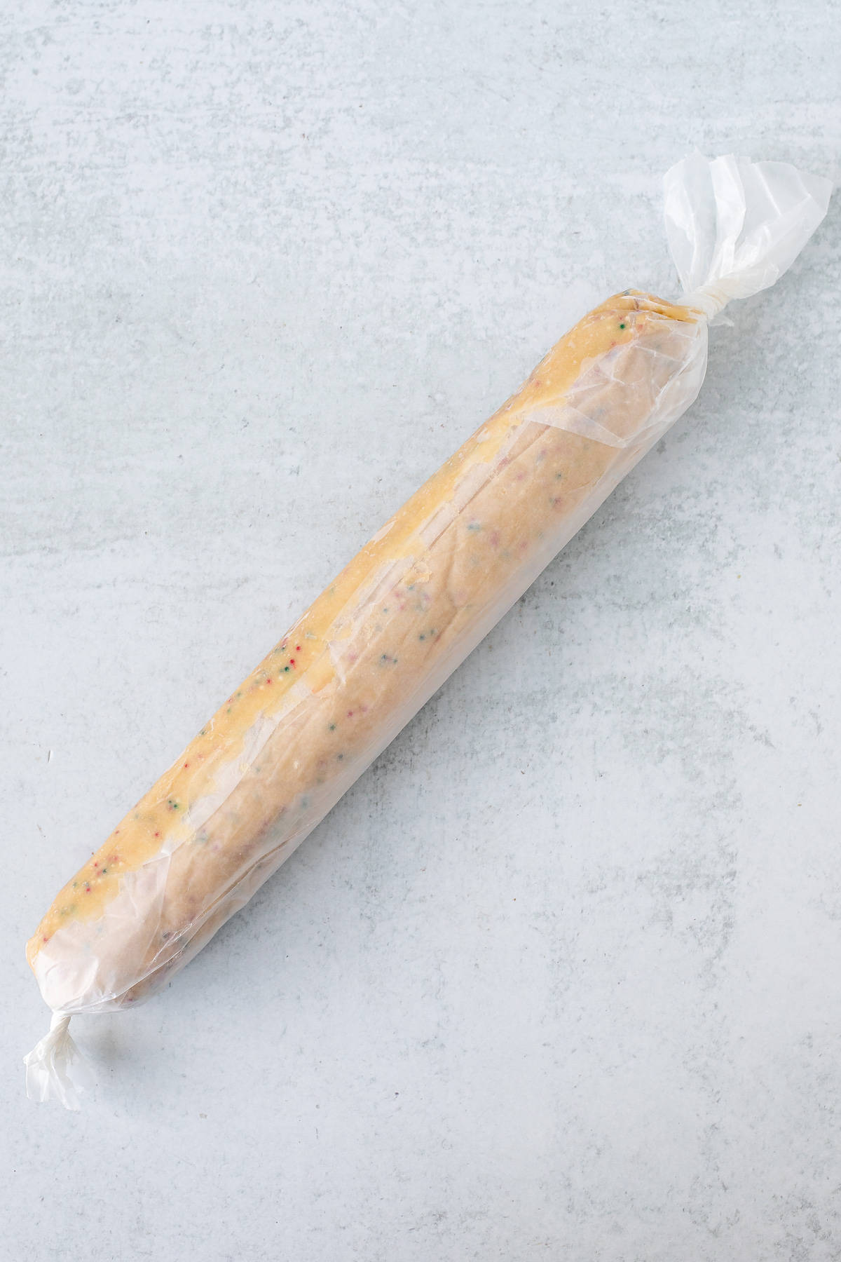 Cookie dough log wrapped in wax paper with the ends twisted