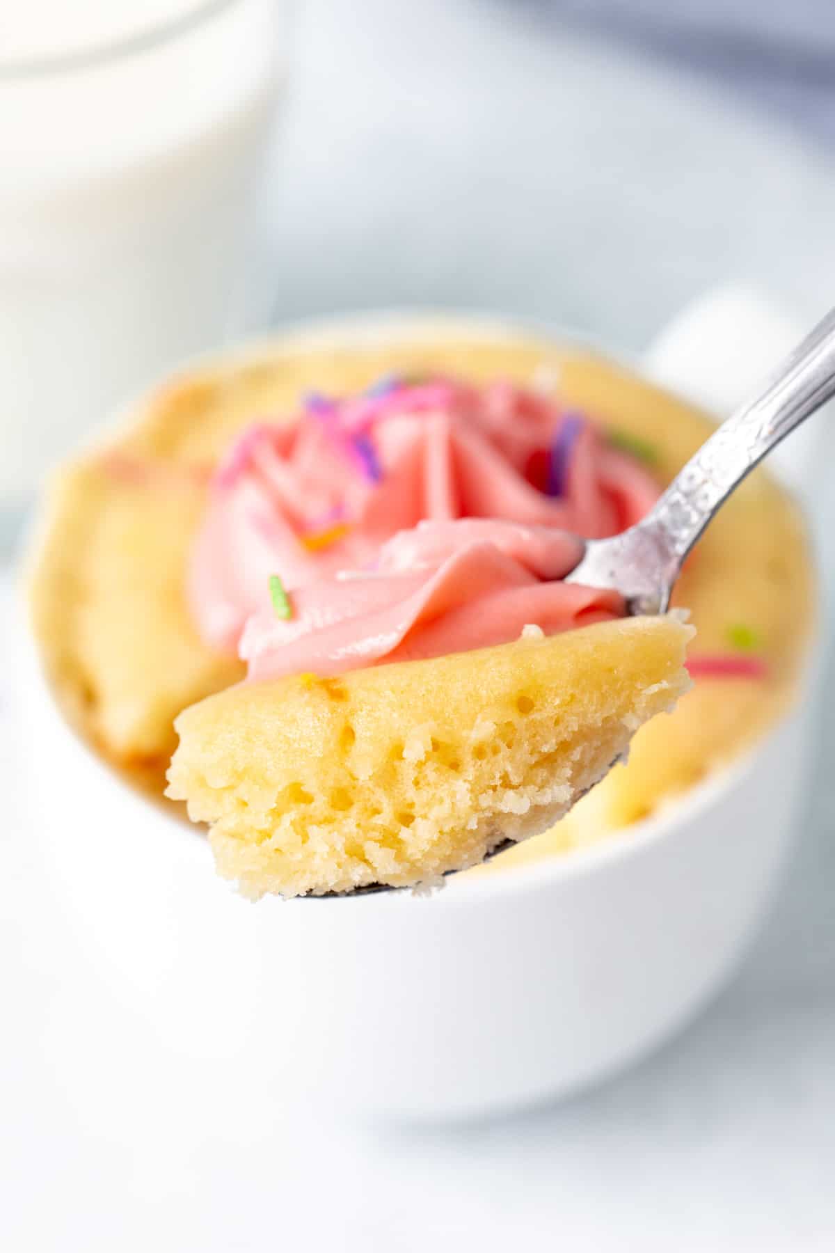 Spoon with a scoop of vanilla cake made in a mug
