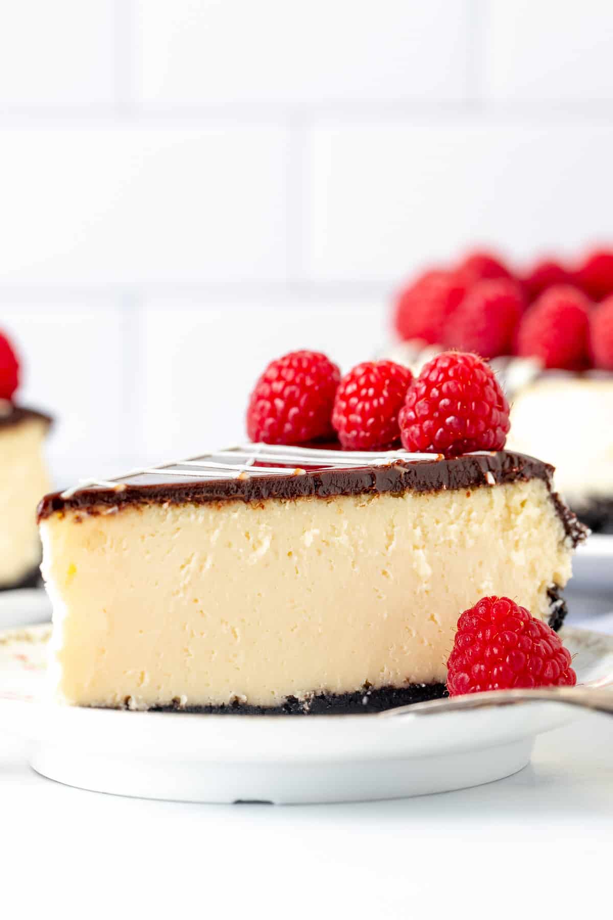 Slice of white chocolate cheesecake with Oreo crust and chocolate topping