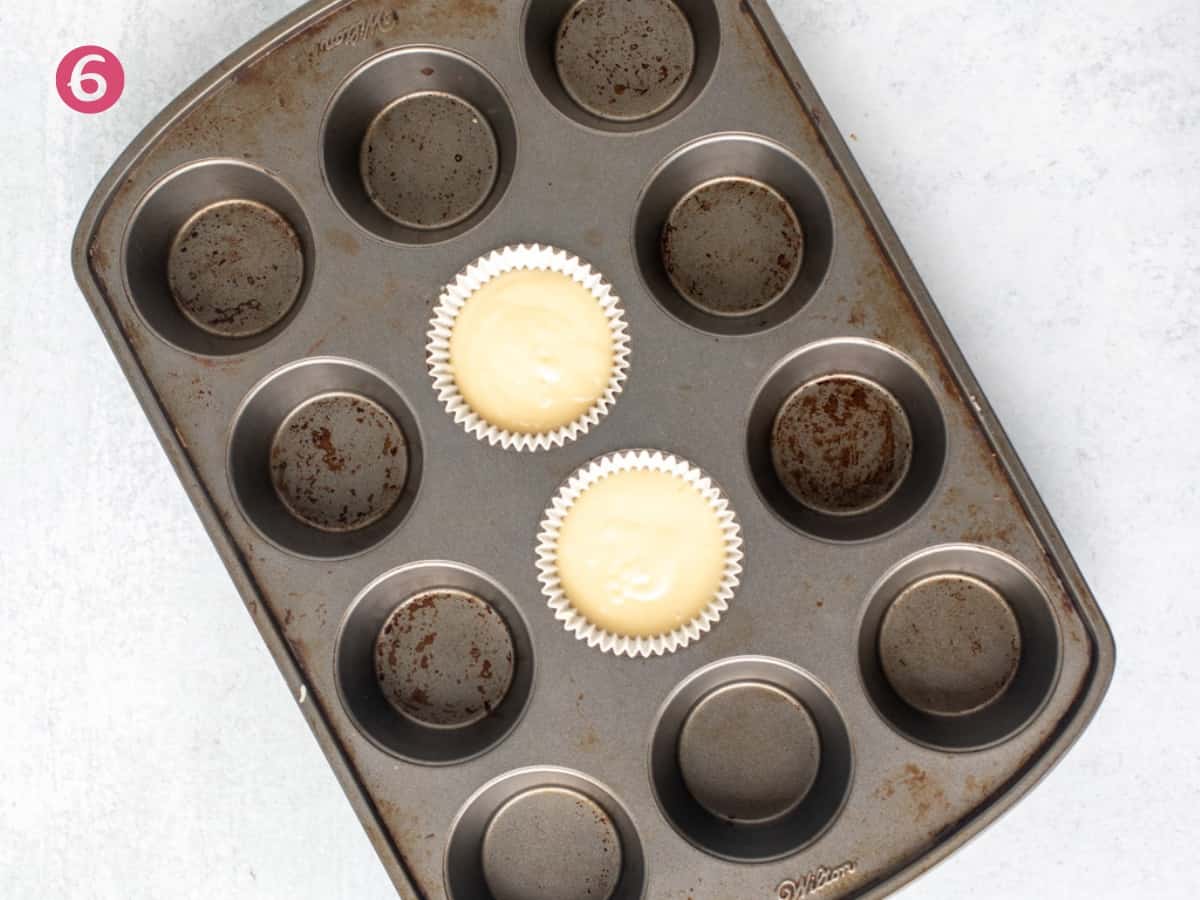 Muffin pan with two unbaked vanilla cupcakes