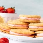 Plate of lemon sandwich cookies with strawberry frosting, with cookies on top of each other