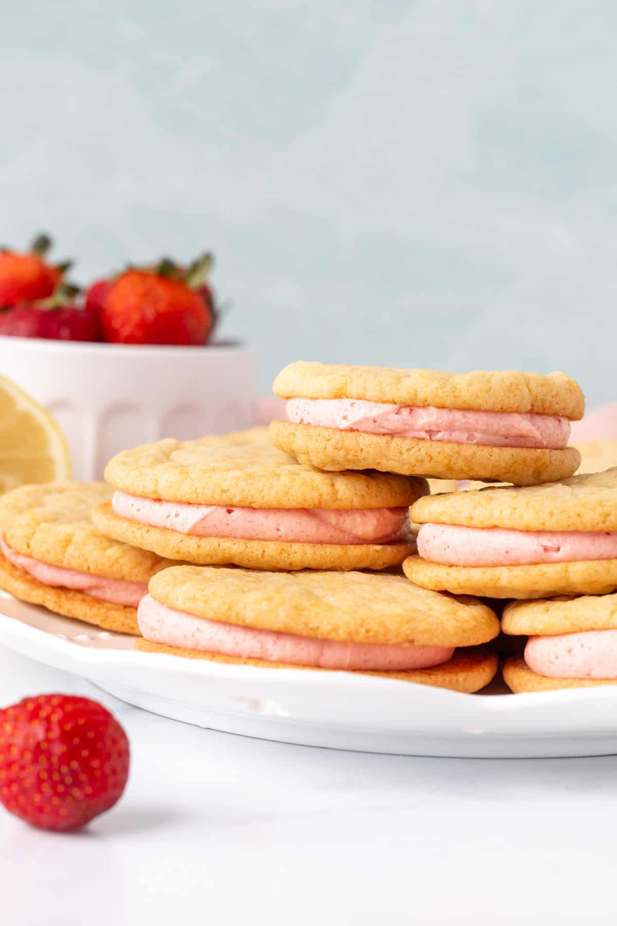 Plate of lemon sandwich cookies with strawberry frosting, with cookies on top of each other