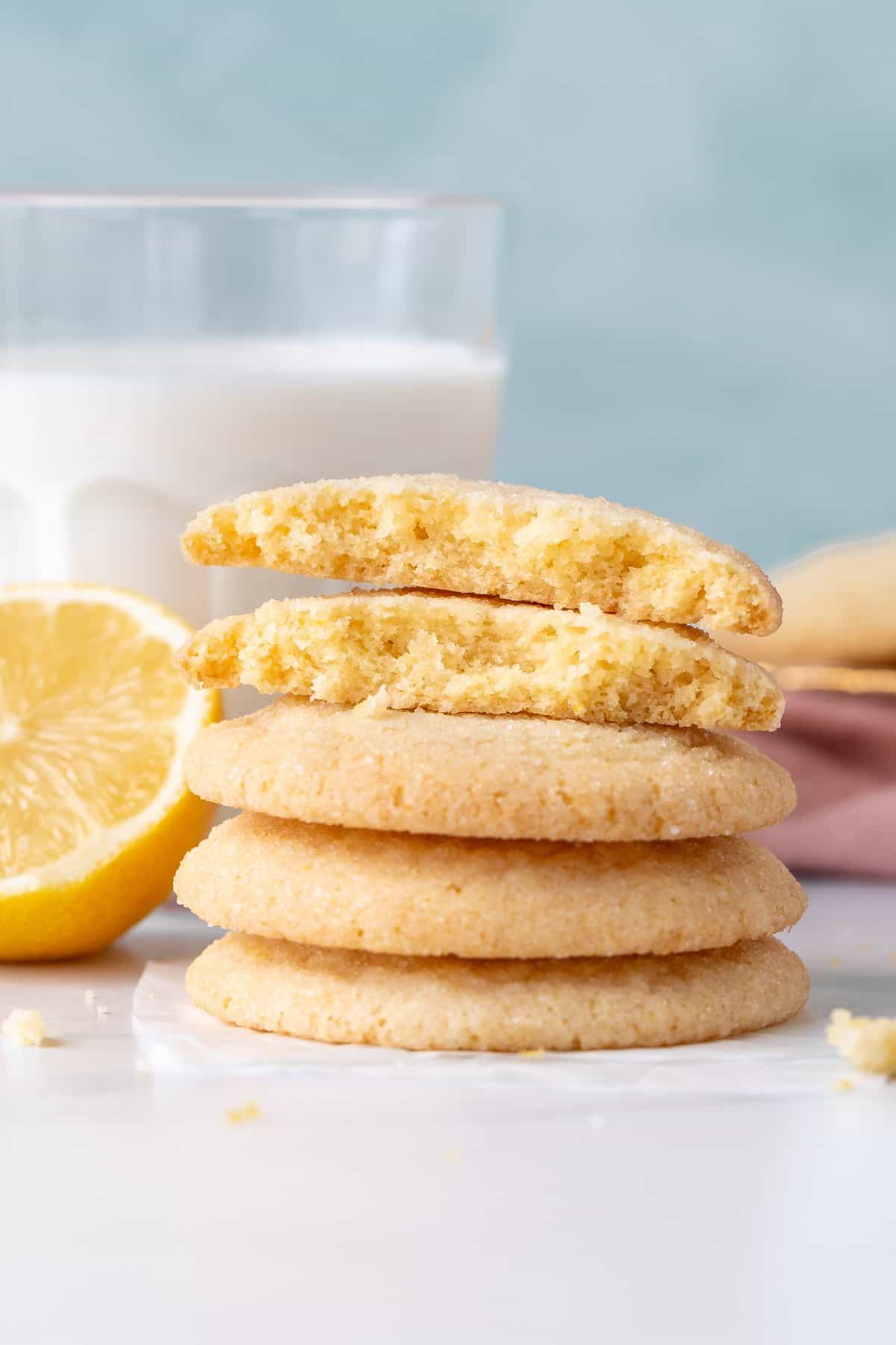 Lemon sugar cookies stacked on top of each other, with top cookie broken in half