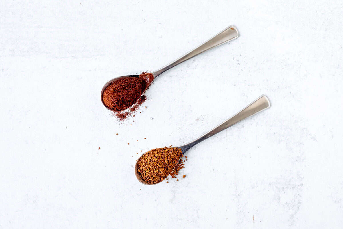 Spoonful of small instant coffee granules and spoonful of larger instant coffee granules.