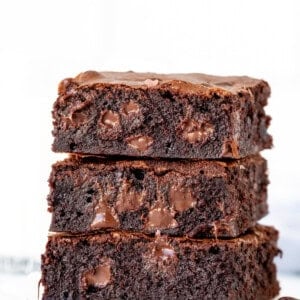 Stack of three gooey brownies with melted chocolate chips
