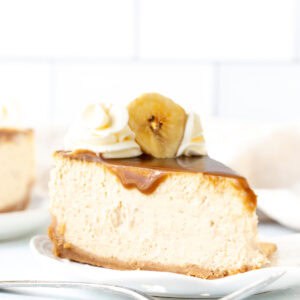 Slice of banoffee cheesecake with caramel, whipped cream and a banana slice on top