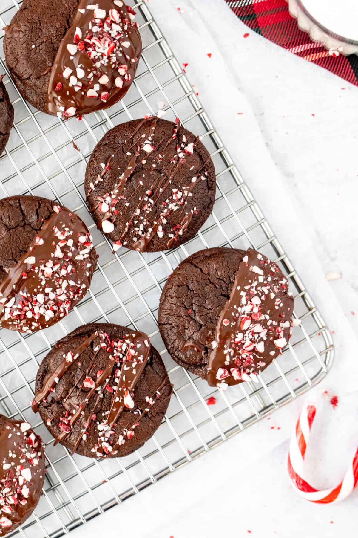 chocolate peppermint cookies on a cooling rack, topped with chocolate and crushed candy canes.
