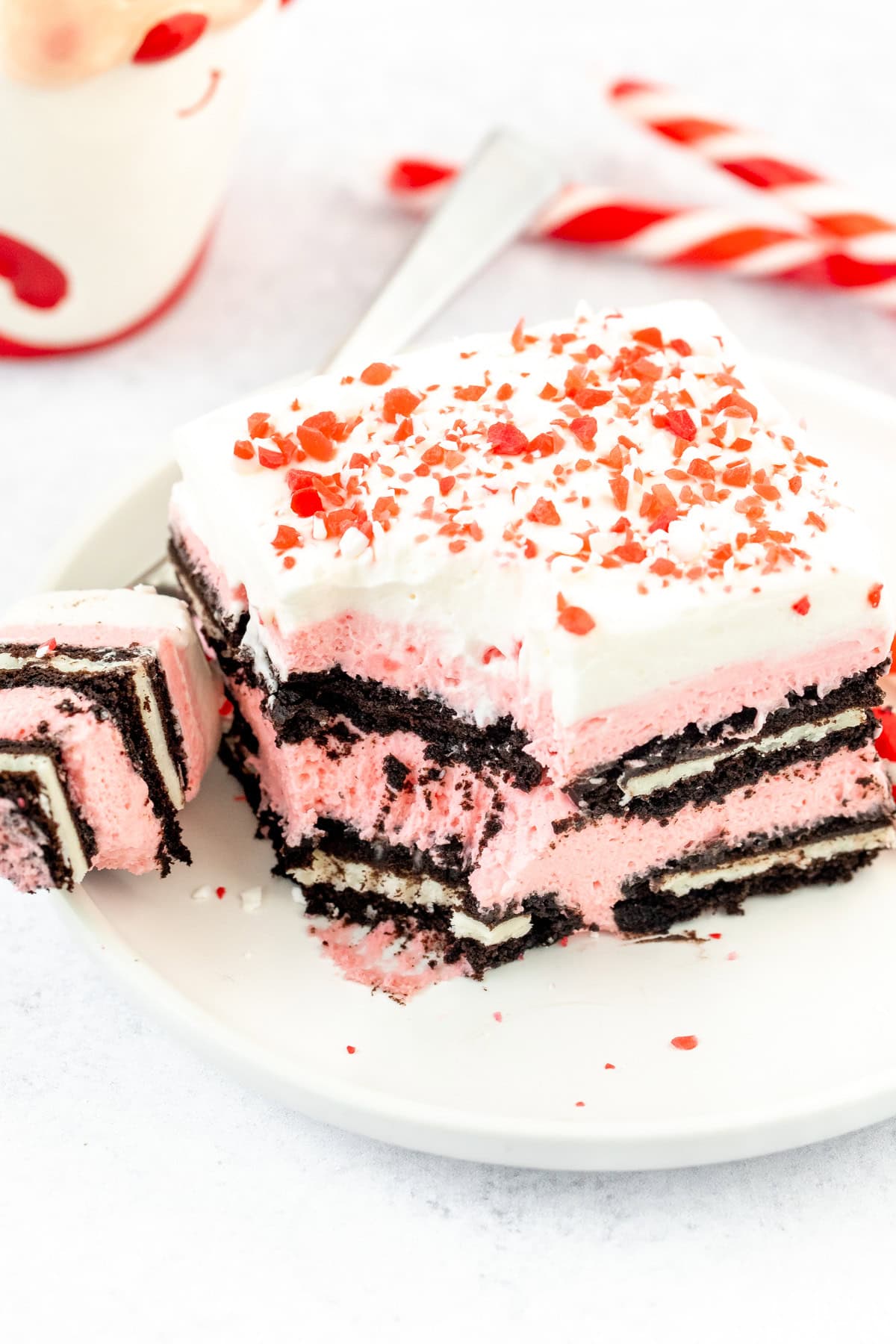 Slice of peppermint Oreo icebox cake, with whipped cream and crushed candy canes on top