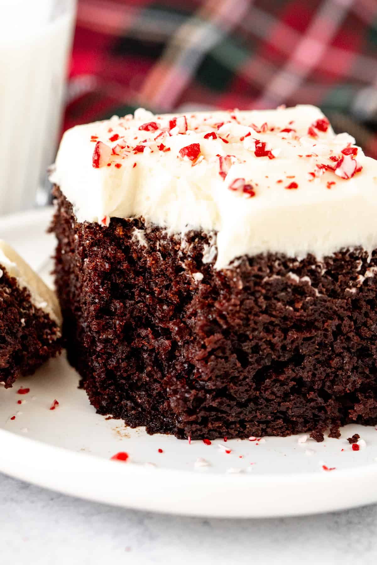 Slice of chocolate cake with white chocolate peppermint frosting and crushed candy canes on top
