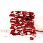 bakery style red velvet cookies, broken in half and stack on top of one another