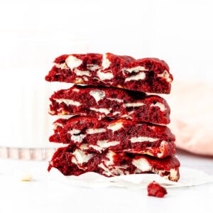 bakery style red velvet cookies, broken in half and stack on top of one another